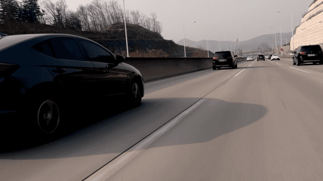 Cars running on a highway with a view of the mountains