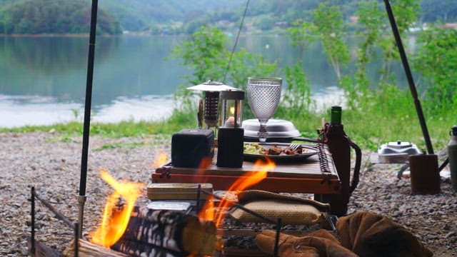 Enjoying a glass of wine at a lakeside campsite with a campfire