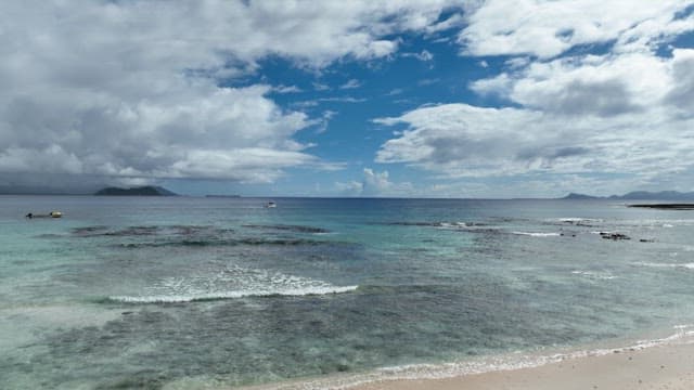 Emerald sea with a horizon visible under a sunny sky with white clouds