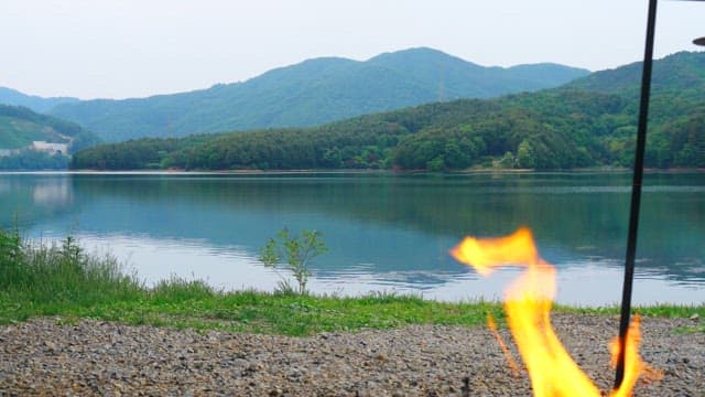 Campfire on a lakeside with a mountainous backdrop