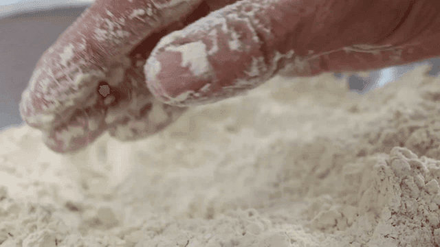 Touching buckwheat flour by hand in a metal bowl