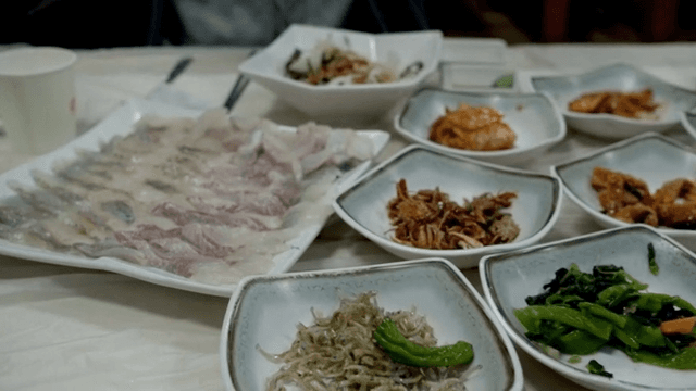 Variety of raw fish and Korean side dishes on table