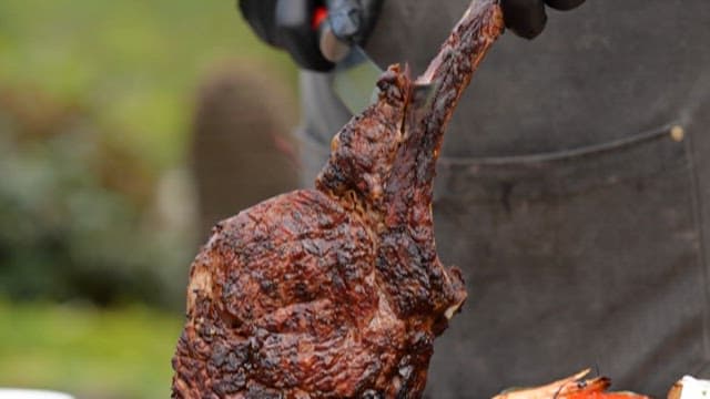 구워진 스테이크를 들고 자르는 사람