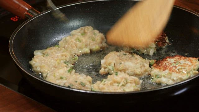 Cooking donggeurangtang in an oiled frying pan with a wooden spatula and spoon