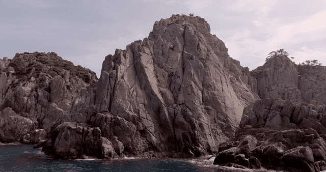 Rocky cliffs by the sea under a cloudy sky