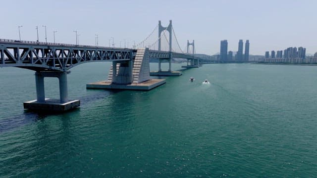 Yachts passing under the Gwangan Bridge on a clear day with lots of cars