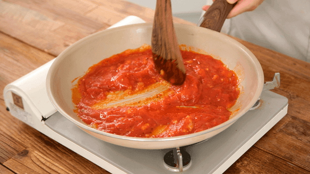 Spatula stirring tomato sauce in pan