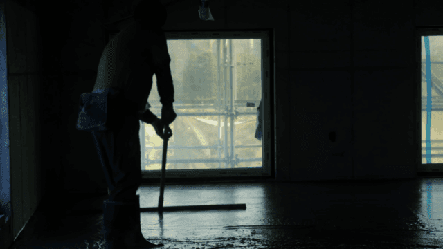 실내에서 콘크리트 바닥을 고르는 작업자