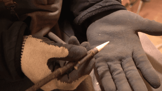 연필 모양 나무를 잡고 있는 장갑 낀 손