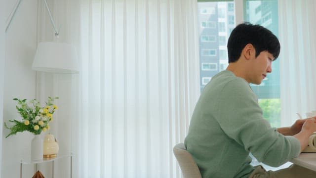 밝은 거실 창가에서 스마트폰을 사용하는 남자