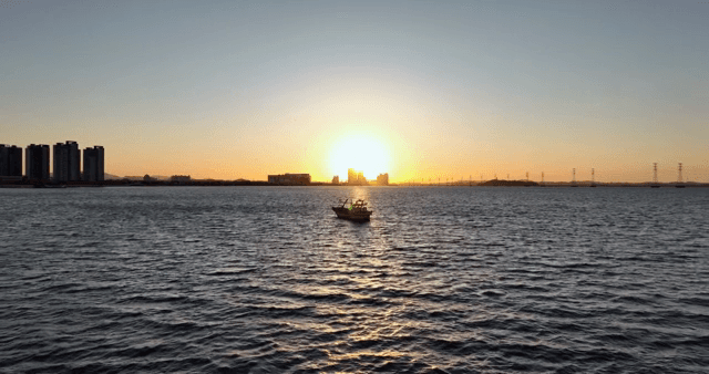 A boat on the sea at sunset with cityscape
