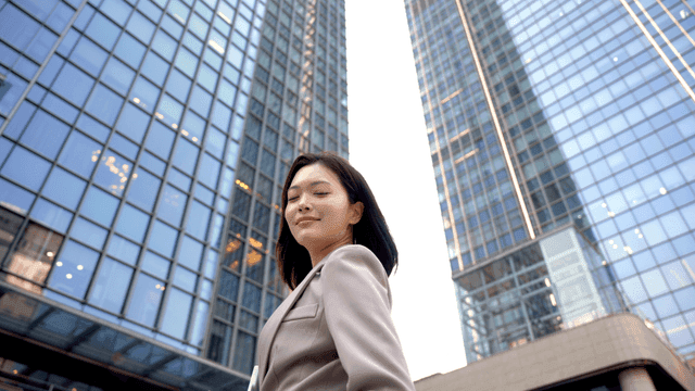 Confident female office worker in front of high-rise building