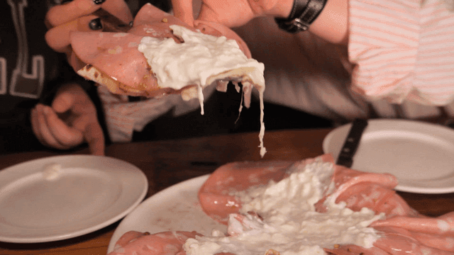 Person serving mortadella pizza onto plate