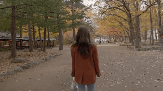 가을 풍경 속 길을 걷는 여성