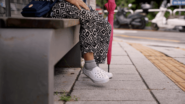 우산을 들고 벤치에 앉아 있는 사람