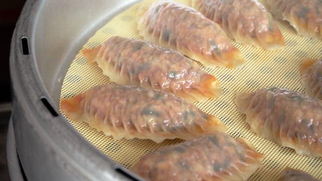 Kimchi dumplings steaming in a steamer in the kitchen