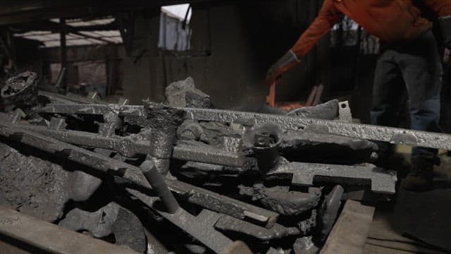 Worker handling metal piece in a factory