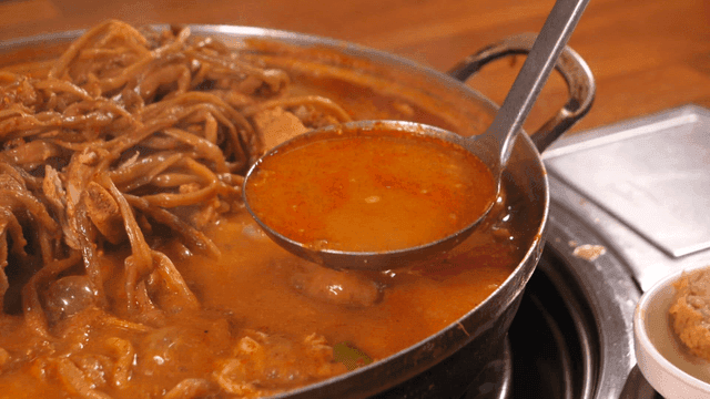 One ladle of pork backbone stew topped with sweet potato stems