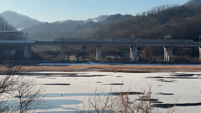 Train crossing a bridge over a frozen river