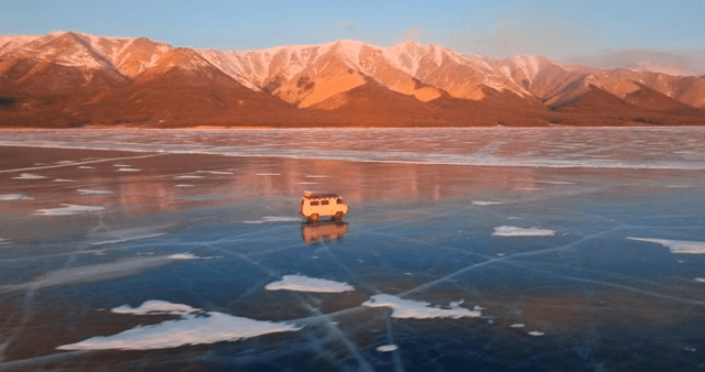 Van driving on a frozen lake at sunset