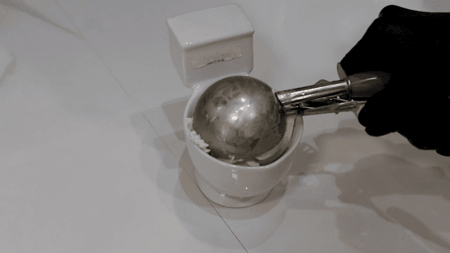 Ice cream being scooped into a small bowl