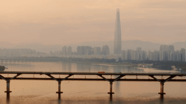 City skyline with a river and bridge at sunset