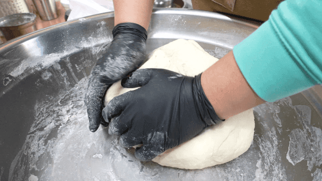 Hands kneading dough in a large bowl