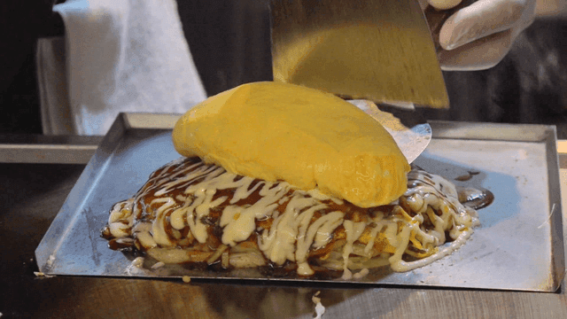 Omelette being placed on okonomiyaki