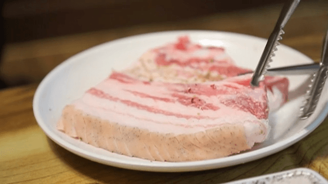 흰 접시에 놓인 시즈닝된 삼겹살