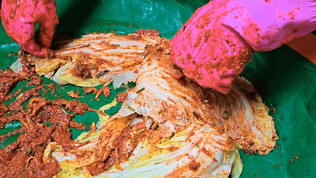 Kimchi being prepared with spicy seasoning