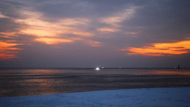 Boat on the sea during a vivid sunset with snowy shore