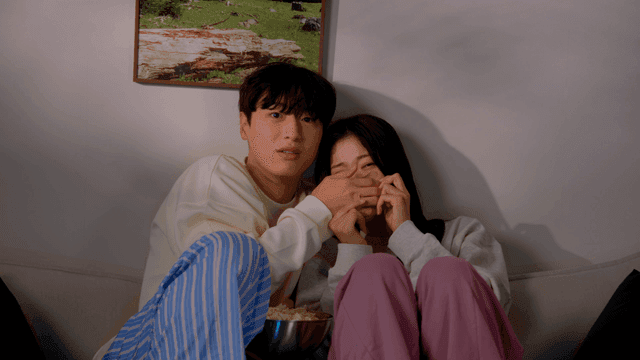 Couple watching horror movie eating popcorn on sofa