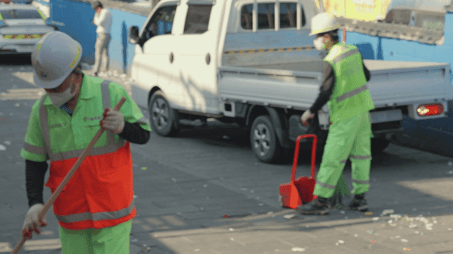 주차된 차량 근처에서 일하는 거리 청소부들