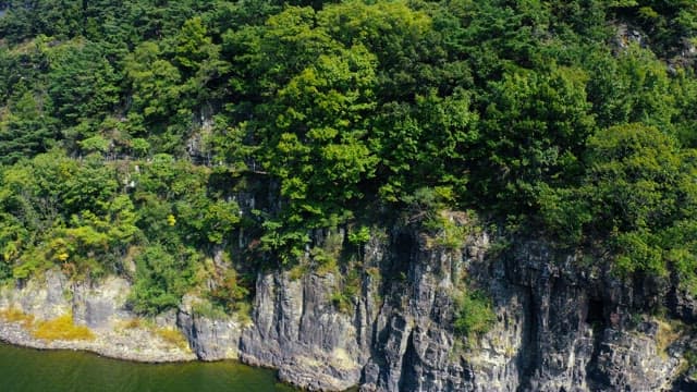 Lush green mountains by a serene river under a clear sky