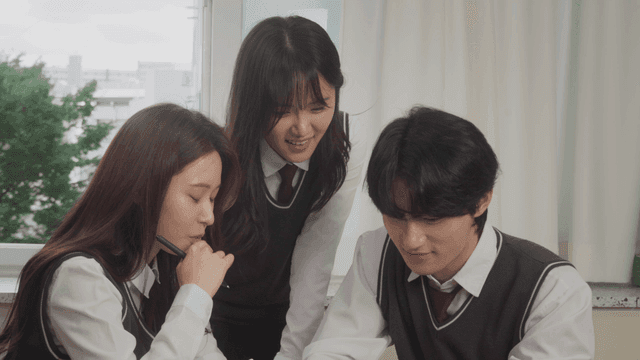 휴대폰을 함께 보며 웃음을 나누는 학생들