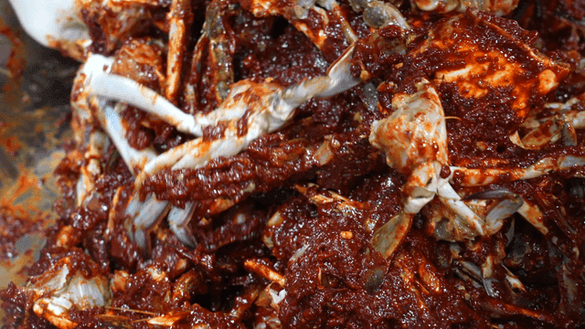 Mixing marinated crabs with spicy sauce