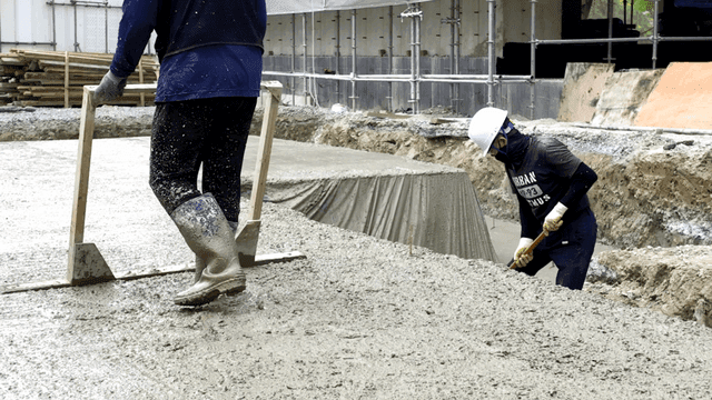 건설 작업자들이 젖은 콘크리트를 고르는 모습