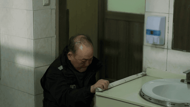 Man sitting on floor in bathroom using his cell phone