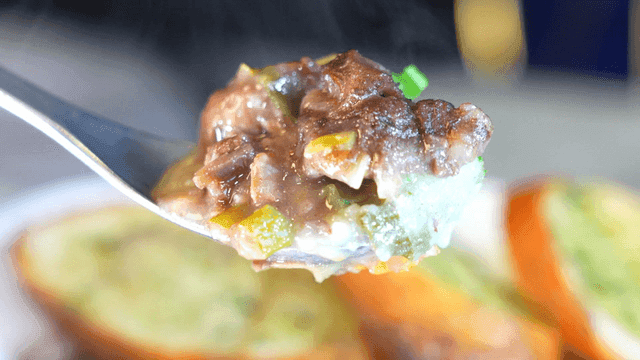 Spoon scooping out rich beef bourguignon with vegetables