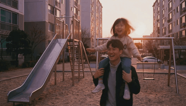 Father and daughter playing on rocking horse at apartment playground