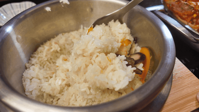 Ladle for mixing nutritious rice cooked in pot with mushrooms and pumpkin