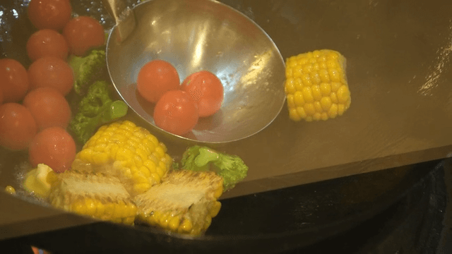 Broccoli, corn, and cherry tomatoes stir-fried in wok