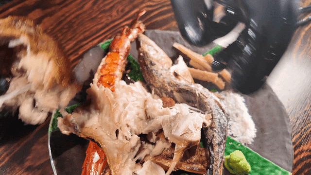 Hands peeling grilled fish on a plate