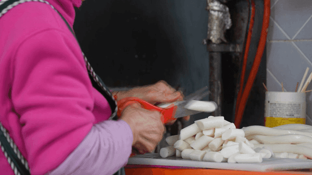 Elderly woman cutting rice cakes with scissors