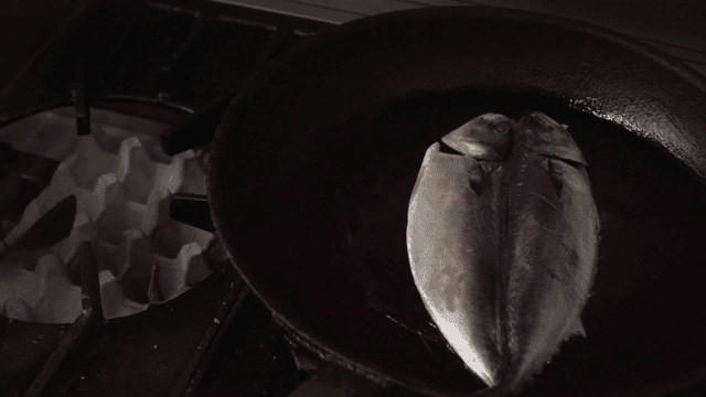 Fish being cooked in a pan on a stove