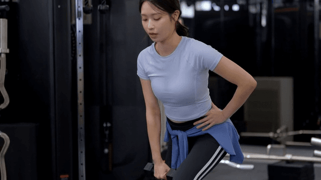 헬스장에서 덤벨을 들고 런지하는 젊은 여성