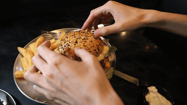Hand preparing burger with french fries