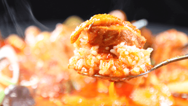 Rice and chicken dipped in spicy braised chicken broth on spoon