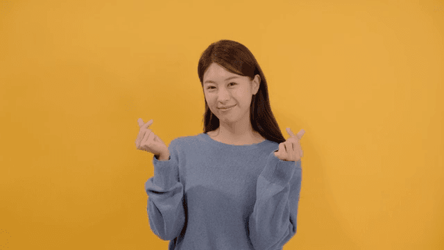 행복한 표정으로 손가락 하트를 만드는 여성