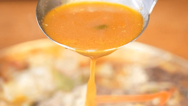 Hearty stew with broth dripping from ladle